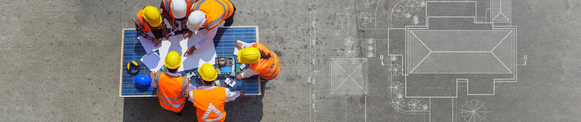 Top view of architectural engineer working on his blueprints with documents on construction site.
